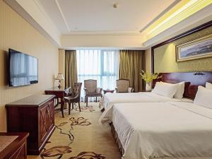 een hotelkamer met 2 bedden en een bureau bij Vienna Hotel Changnan in Nanchang County