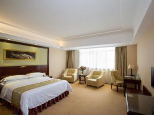 ein Hotelzimmer mit einem großen Bett und Stühlen in der Unterkunft Vienna Hotel Heyuan High-Tech Yi Road in Heyuan