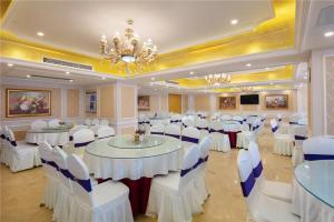 a banquet hall with white tables and chairs and a chandelier at Vienna Hotel Zhengzhou Zhongyuan Futa in Zhengzhou +30 photos
