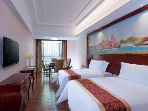 a hotel room with two beds and a flat screen tv at Vienna International Hotel Heyuan Yajule Garden in Heyuan