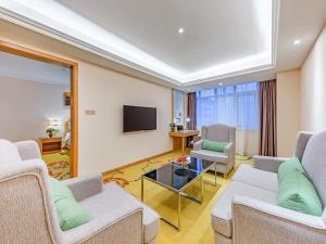 uma sala de estar com sofás e uma televisão de ecrã plano em Vienna Hotel Jinan West Railway Station Lanxiang Road Quanli Auto Parts City Shop em Jinan