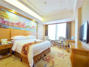 a hotel room with a bed and a flat screen tv at Vienna International Hotel Meizhou Dingzi Bridge in Meizhou