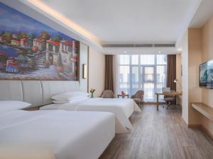 a hotel room with two beds and a painting on the wall at Vienna Hotel Hangzhou Yuhang Linping in Yuhang