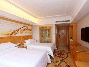 a hotel room with two beds and a flat screen tv at Vienna Hotel Zhongshan West District in Zhongshan