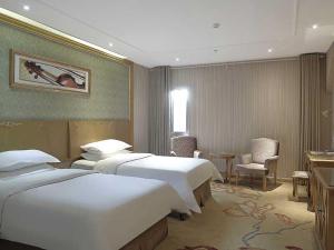 a hotel room with two beds and a table and chairs at Vienna Hotel Suzhou Luokou Metro Station in Suzhou