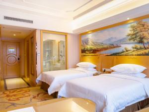 NianbalianにあるVienna International Hotel Shanghai Pudong New District Dishui Lake Univeristy Cityの壁に絵画が飾られた部屋のベッド2台