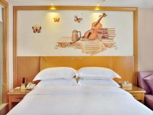 a bedroom with a bed with a guitar on the wall at Vienna Hotel Anhui Mingzhu Square in Ershilipu