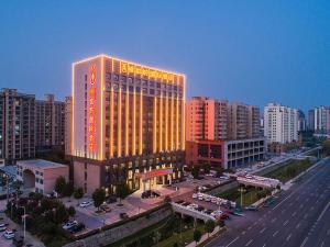 a lit up building in a city with buildings at Vienna International Hotel Xinyang Yangshan New District in Xinyang