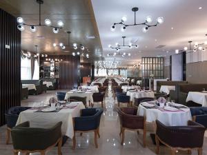 a restaurant with white tables and chairs and chandeliers at Vienna Hotel(Haikou International Convention and Exhibition Center) in Haikou