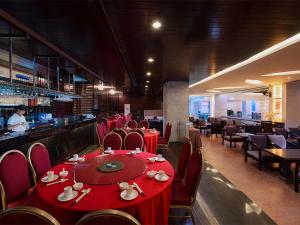 un ristorante con tavoli e sedie rossi e un bar di Vienna Hotel - Guangzhou South Railway Station Branch a Canton