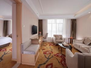 a hotel room with a bed and a living room at Vienna Hotel (Jieyang Longwei) in Jieyang