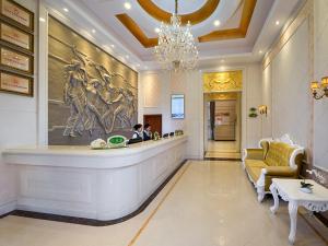 恵州市にあるVienna International Hotel Huizhou Daya Bay Century Cityのロビーのカウンターに座って2名