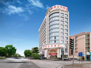 a tall white building on a city street with a traffic light at Vienna Hotel Guangdong Zhongshan Nanlang in Zhongshan