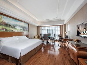 a hotel room with a large bed and a desk at Vienna International Hotel Xinyang Yangshan New District in Xinyang +7 photos