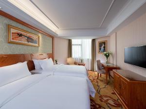 a hotel room with a large bed and a flat screen tv at Vienna Hotel Mix City in Shenzhen