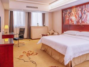 a hotel room with a large bed and a television at Vienna Hotel Jiangxi Yingtan International Glasses City in Yingtan