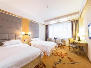 a hotel room with two beds and a desk at Vienna Hotel Zhanjiang Coast Avenue in Zhanjiang
