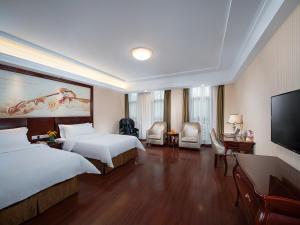 Vienna Hotel Chongqing Chuangyi Park في Shiping: غرفة فندقية بسريرين وتلفزيون بشاشة مسطحة