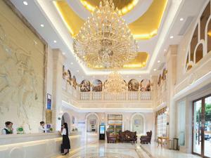 a woman standing in a lobby with a large chandelier at Vienna Classic Hotel Ganzhou Meilin in Ganzhou