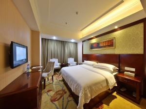 a hotel room with a bed and a flat screen tv at Vienna Hotel Zhangjiajie North Railway Station in Zhangjiajie