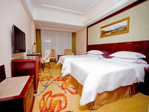 宝安にあるVienna Hotel Shenzhen Shiyan Shilong Communityのベッド2台と机があるホテルの部屋