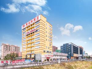 a tall yellow building with a sign on top of it at Vienna Hotel Shenzhen Gongming Bus Station in Kung-ming