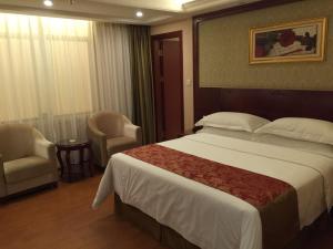 a hotel room with a large bed and a chair at Vienna Hotel Shunde Longjia Exhibition Center in Shunde