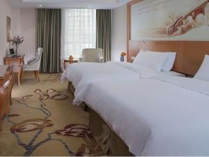a hotel room with two beds and a desk at Vienna Hotel(Zhangzhou Jiaomei WanYi square store) in Longhai