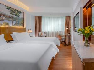 a hotel room with two white beds and a desk at Vienna 3 Best Hotel Shenzhen Airong Road in Shenzhen