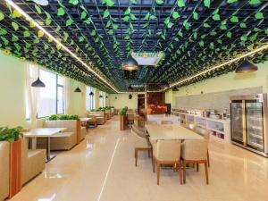 un restaurant avec des tables, des chaises et des plafonds verts dans l'établissement Vienna Hotel Shenzhen Longgang Ainan Road, à Longgang