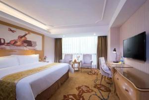 a hotel room with a large bed and a flat screen tv at Vienna Hotel Meizhou Xingning District Plaza in Libei