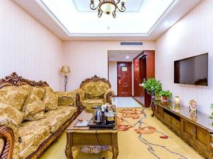 Vienna Hotel Anhui Hefei Sanxiaokou في خفي: غرفة معيشة مع أريكة وتلفزيون