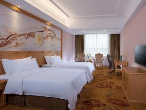 a hotel room with two beds and a flat screen tv at Vienna Hotel conghua jiangpu street branch in Huadu