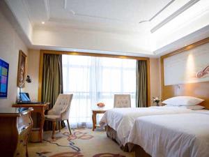 a hotel room with two beds and a desk and a window at Vienna International Hotel Xuancheng Garden in Xuanzhou