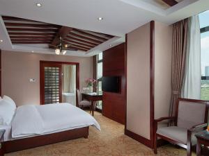 a bedroom with a bed and a desk and a television at Vienna Hotel Kunming North Caiyun Road Asia in Kunming