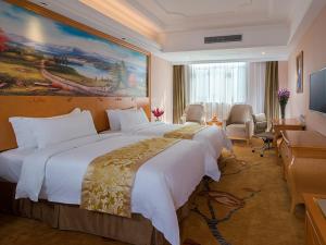 a hotel room with a large bed and a large painting at Vienna Hotel Foshan Ceramic City in Foshan
