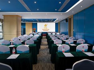 a conference room with tables and chairs and a screen at Vienna Hotel(Haikou International Convention and Exhibition Center) in Haikou