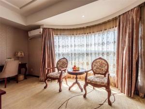 - un salon avec deux chaises, une table et une fenêtre dans l'établissement Vienna Hotel Hangzhou Yuhang Linping, à Yuhang