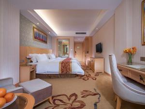 FenghuangweiにあるVienna Hotel Shenzhen Fuyong Villageの大きなベッドとリビングルームが備わるホテルルームです。