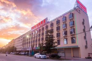 a building on a street with a sunset in the background at Vienna Hotel Sanya Yalong Bay Qianguqing in Sanya