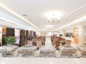 un restaurant avec des tables et des chaises et un lustre dans l'établissement Vienna Hotel Ningbo Ninghai, à Shang-ts'un