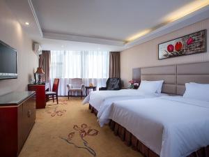 Cette chambre comprend deux lits et une télévision. dans l'établissement Vienna Hotel Guangzhou Dekang Road, à Canton