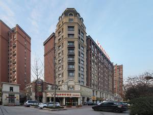 a tall building on a city street with cars at Vienna Hotel Shandong Qingdao Chengyang in Xifu
