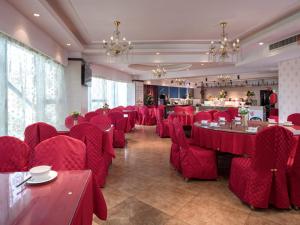 un comedor con sillas y mesas rojas y un restaurante en Vienna International Hotel Changzhou Hutang en Changzhou