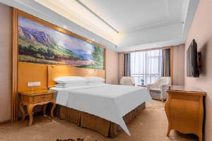a hotel room with a bed and a painting on the wall at Vienna Hotel Foshan Airport in Foshan