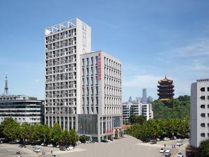 a tall white building in a city with cars at Vienna Hotel Wuhan Yellow Crane Tower in Wuhan