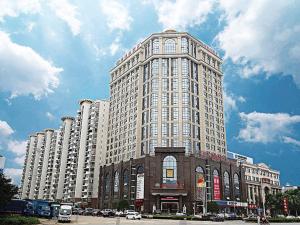 een groot hoog gebouw met auto's geparkeerd voor het bij Vienna Hotel Changnan in Nanchang County