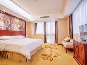 a hotel room with a large bed and a flat screen tv at Vienna Hotel Jiangxi Yingtan International Glasses City in Yingtan