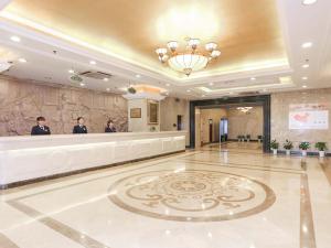 um lobby de hotel com três pessoas em pé em um balcão em Vienna International Hotel - Hangzhou Wulin Square Branch em Hangzhou