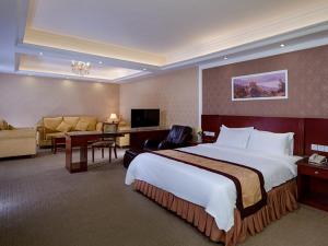 een hotelkamer met een groot bed en een bureau bij Vienna Hotel Dongguan Songshan Lake in Dongguan